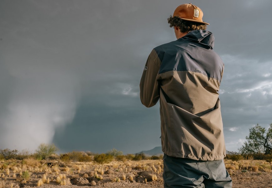 A storm chaser man taking a photo of a twister in M's Stretch Voyagr Jacket