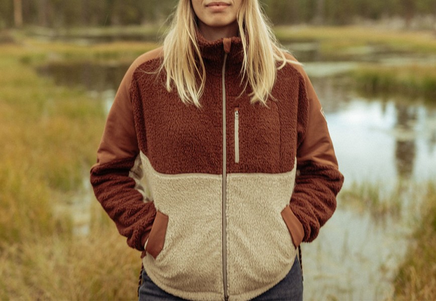 A woman stands next to a pond in womens fall jacket