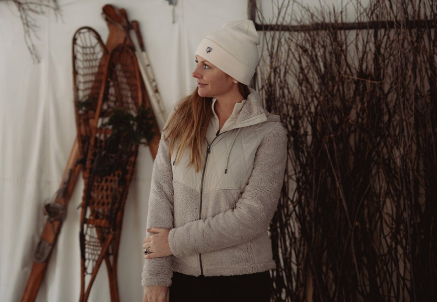 A woman stands next to old snowshoes in womens fall jacket