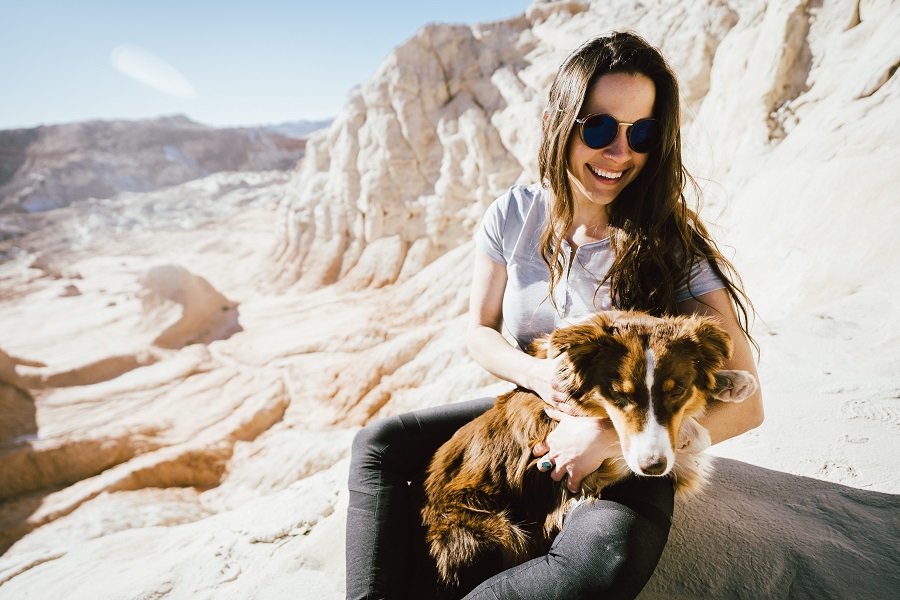 A woman wearing KUHL sun protective Clothing, holds a dog.