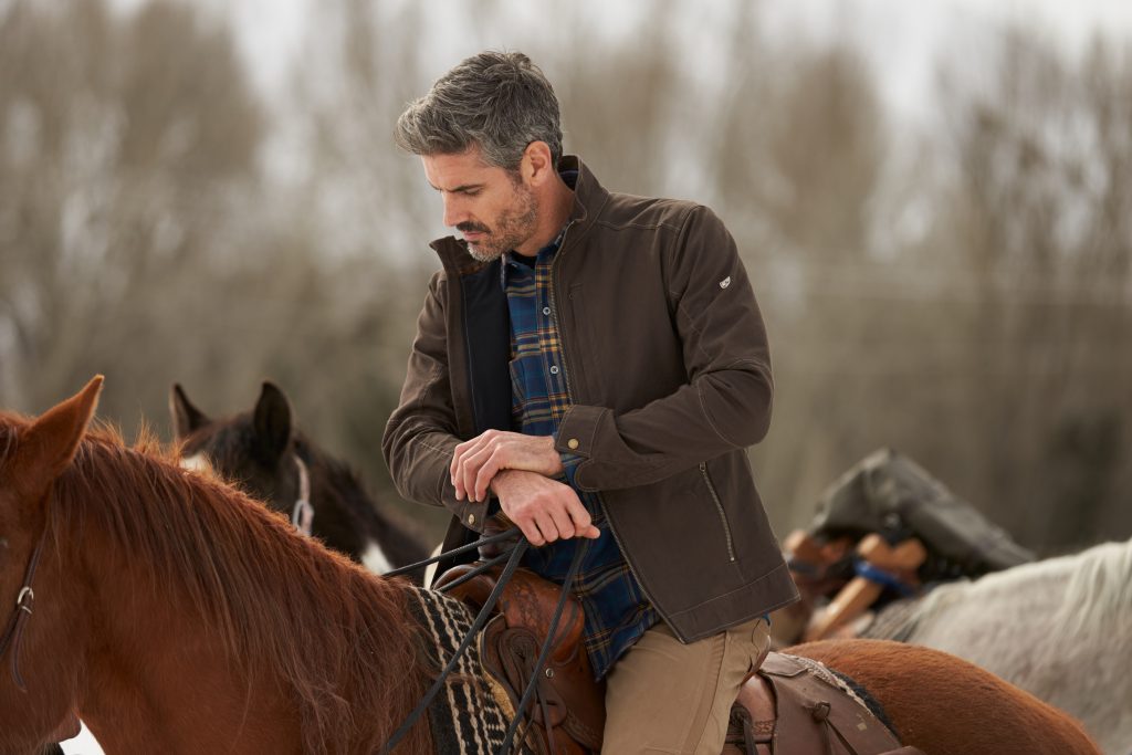 Man dressed in KUHL clothing riding a horse in winter.