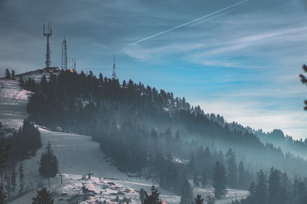 An image of Bogus Basin in Idaho, USA. A hill covered in snow with pine trees.