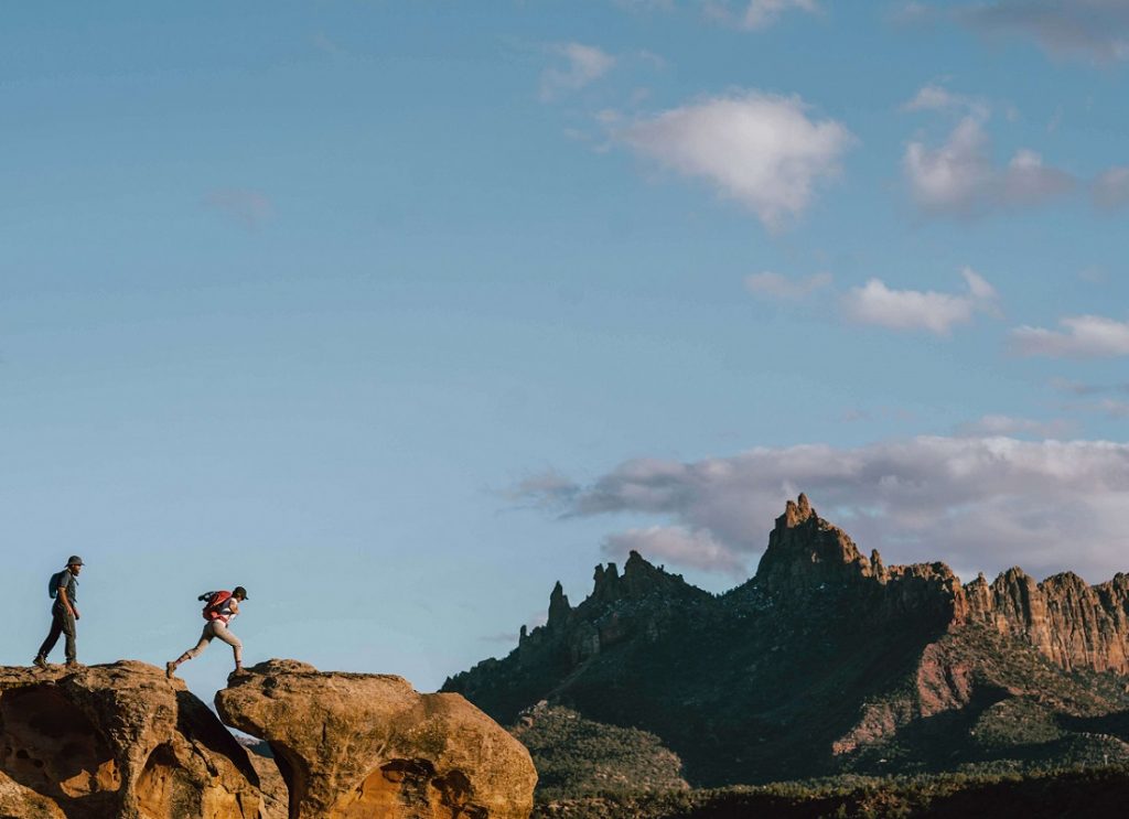 man and woman walking on rocks under the blue sky