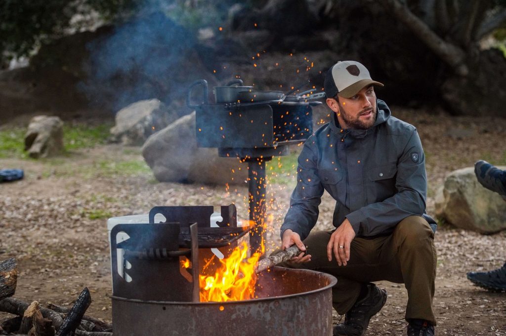 man standing next to a fired up outdoor grill