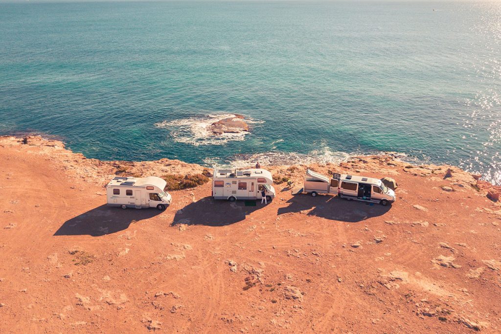 three white RVs near sea at daytime