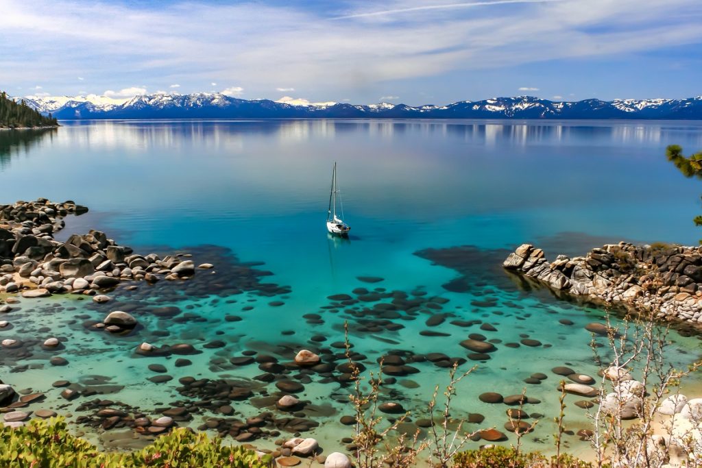 white boat on blue body of water with rocks