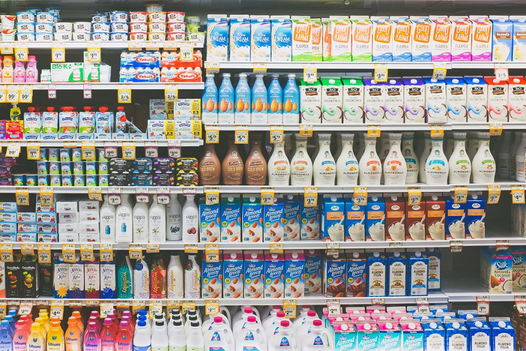 assorted cartoons of almond milk in white store refrigerator