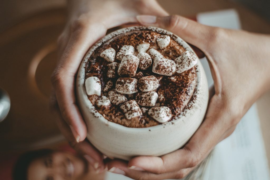 person holding white cup with marshmellows