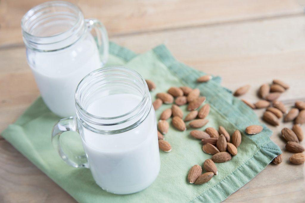 almond milk in two jars next to almonds