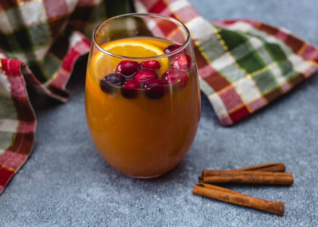 orange liquid in glass with orange slice and red berries on top