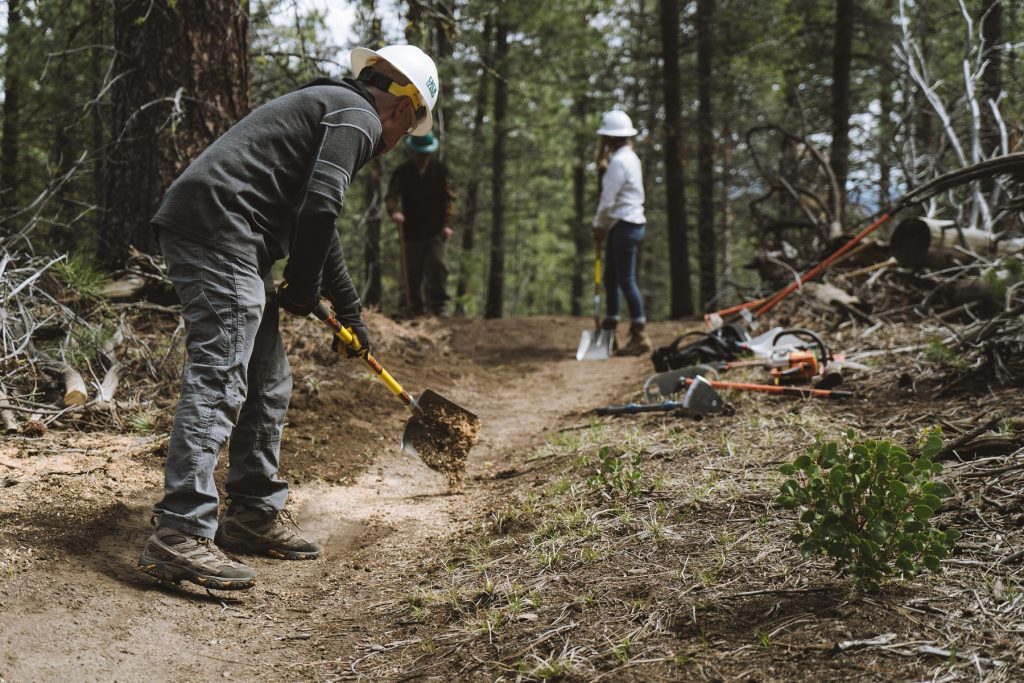 Vanessa and Glenn working on mountain biking trail while wearing KUHL clothing