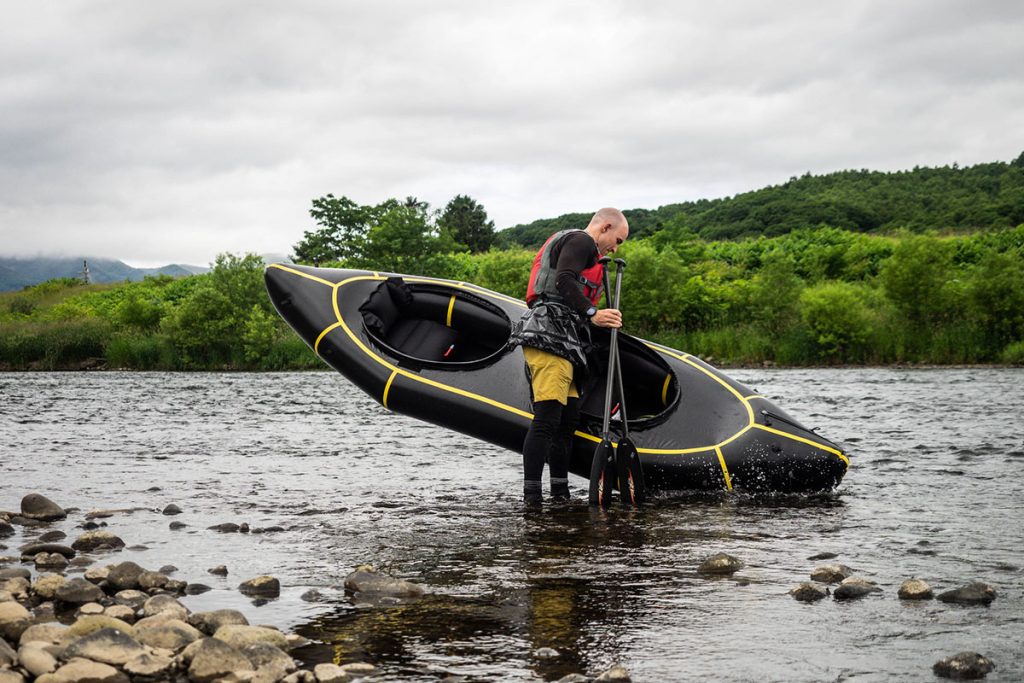 Man carrying a Packraft out of river