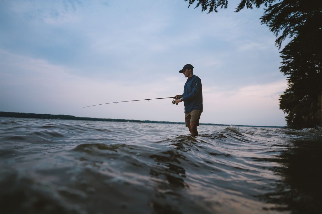 A man in outdoor clothing finds a good fishing spot